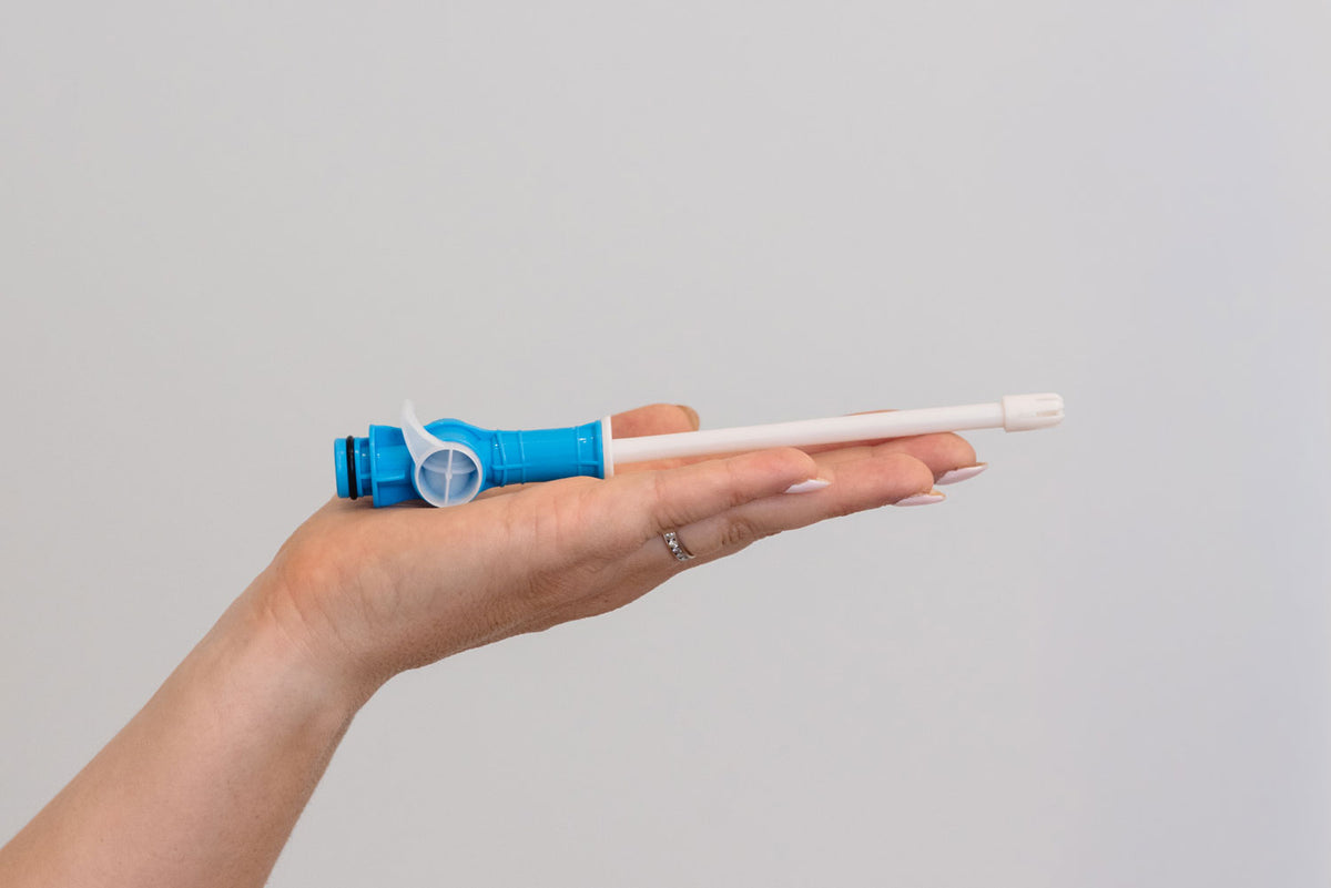 A hand holding a dental device against a plain light gray background. #Product_Aero® HVE SE (Aspetico, DCI Comfort, Engle, Marus, Midmark, Peloton & Crane & Royal) #Product_Aero® HVE SE (A-dec) #Product_Aero® HVE SE (Belmont, DentalEz & Forest)
